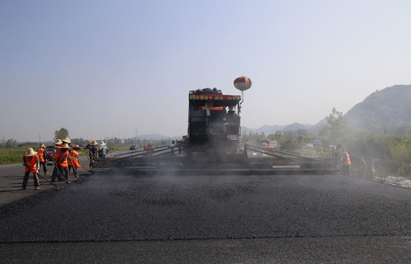 2019年8月，宜春經(jīng)開區(qū)S311路面攤鋪現(xiàn)場，工友們輔助路面兩側(cè)的分料、補窩等作業(yè)